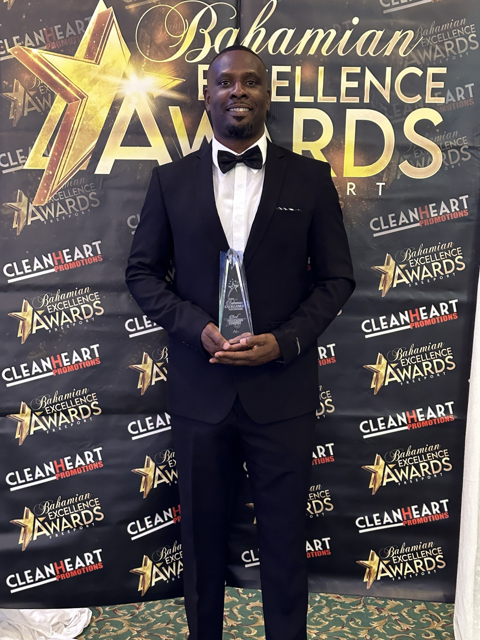 Dennis Deleveaux holding his Bahamian Excellence Award